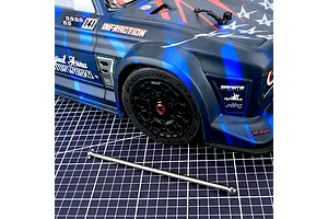Method RC titanium centre rear driveshaft laid out on a grid cutting mat in front of an Arrma Infraction RC car body.