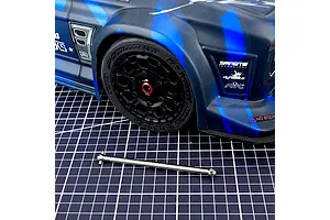 Method RC titanium driveshaft placed on a cutting mat in front of a blue and black RC car body and wheel.
