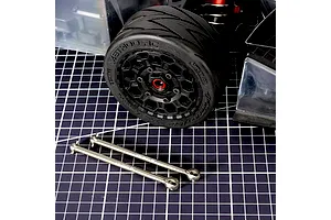 Method RC titanium CVD axle shafts laid out on a grid cutting mat in front of an RC car wheel and chassis.
