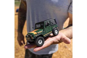 Green Axial SCX30 Jeep CJ-7 Renegade RC rock crawler held in a person's hand outdoors.