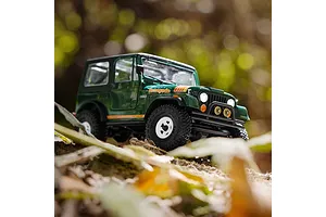Green Axial SCX30 Jeep CJ-7 Renegade RC rock crawler driving outdoors on an uneven dirt and foliage background.