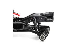 Close-up studio view of the black plastic chassis, axle, suspension shock, and wheel hub assembly of an RC vehicle against a white background.