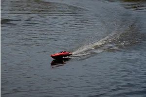 Action shot of the Atrek Riptide red RC speed boat navigating water and creating splashes.
