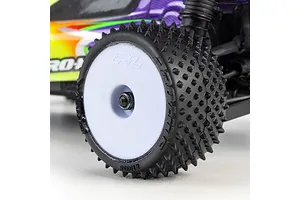 Close-up lifestyle shot of a Pro-Line RC buggy wheel and spiked carpet tyre mounted on a white rim.