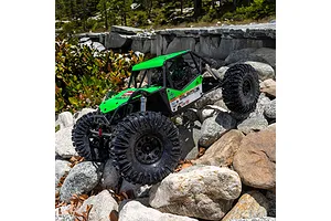 Green RC rock crawler with Chisel II tyres tackling a rocky outdoor trail during daytime.