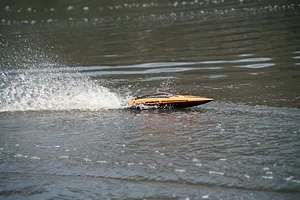Atrek Stealth orange RC speed boat speeding across water, creating a white splash behind it.