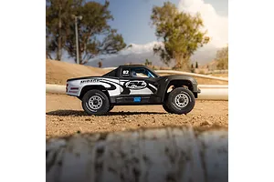 Pro-Line matte black trophy truck body shell mounted on an RC chassis on a dirt track outdoors.
