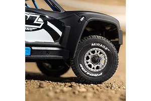 Close-up of matte black RC trophy truck body shell and front tire on a dirt surface