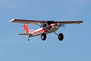 Arrows RC Bigfoot trainer airplane in flight against a clear blue sky background.