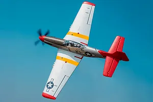 Arrows RC P-51 Mustang warbird RC plane in flight against a blue sky background.