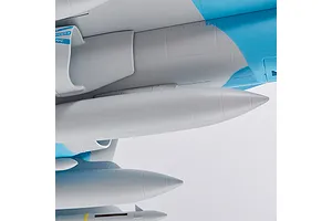Close-up of the underside of the FMS F/A-18 Hornet RC plane showing molded panel lines, blue and grey camouflage, and mounted ordnance details against a white background.