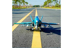 FMS F/A-18 Hornet RC jet airplane sitting on an asphalt road with yellow lane markings outdoors.