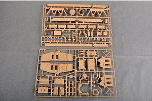 Two tan plastic model kit sprues containing various vehicle parts laid out on a grey surface.