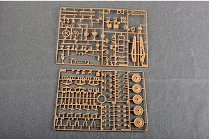 Two tan plastic model kit sprues containing various small parts for a military vehicle model, laid out on a grey surface.