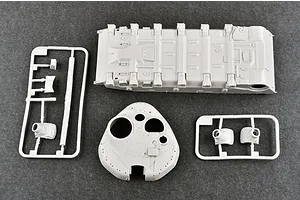 Unassembled plastic model tank parts including the hull, turret, and sprue frames on a dark grey surface.