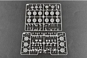 Two grey plastic model kit sprues containing various tank wheels and small mechanical parts on a dark grey background.