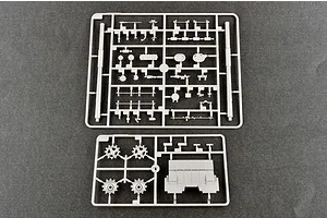 Two grey plastic model kit sprues containing various tank parts, including sprockets and hull sections, laid out on a dark grey surface.