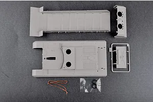 Top-down view of unpainted grey plastic model kit parts for a 1/35 scale Soviet 2S7m self-propelled gun, including hull sections and small accessories.