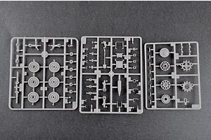 Three grey plastic model kit sprues containing various vehicle parts like wheels and suspension components on a dark grey background.