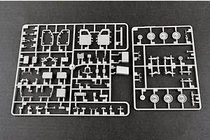 Two grey plastic model kit sprues containing various vehicle parts, including doors, wheels, and suspension components, laid out on a dark surface.