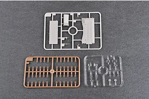 Three plastic model kit sprues for a 1/35 scale tank, including grey, tan, and clear plastic parts on a dark grey background.