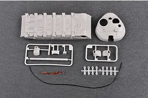 Unassembled plastic model tank parts including the hull, turret, and sprues on a grey background.