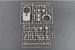 Two grey plastic model kit sprues containing various tank parts, including a turret top, laid out on a dark grey surface.