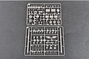 Two grey plastic model kit sprues containing various tank parts, including wheels and gun barrels, laid out on a dark grey surface.