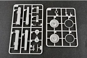 Two grey plastic model kit sprues containing artillery parts, wheels, and gun barrels on a dark grey surface.