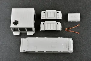 Unassembled grey plastic model kit parts for the Trumpeter 1/35 Russian AT-S Artillery Tractor, including the main chassis, cab, and engine components.