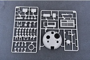 Two grey plastic model kit sprues containing various tank parts, including a large turret shell, laid out on a dark grey surface.