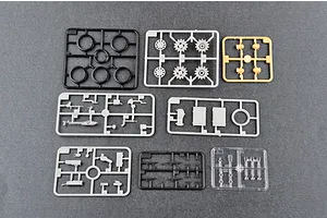 Several plastic model kit sprues for a tank model, including grey, black, tan, and clear parts on a grey background.