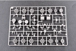 A grey plastic model kit sprue containing various tank parts, including road wheels, sprockets, and suspension components.