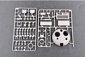 Two grey plastic model kit sprues containing various tank parts, including a turret shell, laid out on a dark grey surface.