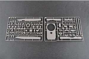 Two grey plastic model kit sprues containing various tank parts, including turret and hull components, laid out on a dark grey surface.