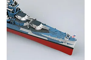 A high-angle view of the bow section of a 1/350 scale USS San Francisco CA-38 model ship, featuring camouflage paint, gun turrets, and a small US flag.