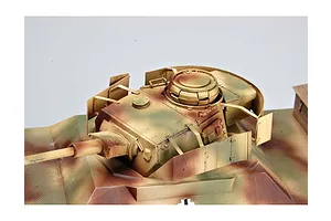 Close-up of a painted 1/35 scale model tank turret with camouflage paint and side armor plating on a white background.