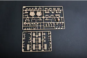 Two tan plastic model kit sprues containing various vehicle parts laid out on a dark surface.