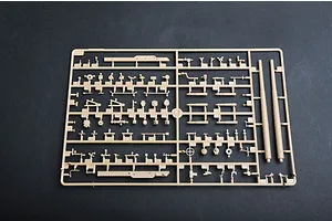 A tan plastic model kit sprue containing various small parts and two long gun barrels for a 1/35 scale military vehicle model.