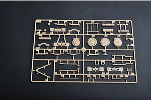 A tan plastic model kit sprue containing various vehicle suspension and chassis parts for a 1/35 scale military model.