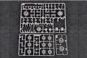 Three grey plastic model kit sprues containing various tank parts like wheels and sprockets on a dark textured background.