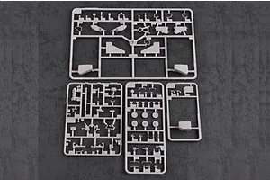 Four grey plastic model kit sprues laid out on a dark textured surface.