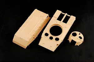 Unassembled tan plastic model kit parts for a BMP-3 tank, including the hull and turret components, on a black background.