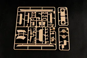 Tan plastic model kit sprue containing various tank parts on a black background.