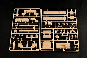 Two tan plastic model kit sprues containing various vehicle parts for a 1/35 scale military model kit on a black background.