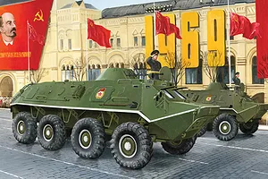 Box art illustration of two green BTR-60PB armoured personnel carriers driving past a building with Soviet flags and a portrait of Lenin.