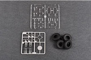 A sprue of clear plastic parts, a sprue of grey plastic parts, and four black rubber tires for a 1/35 scale model kit.