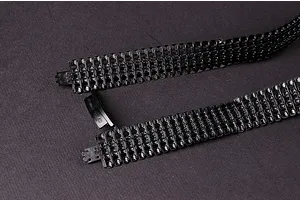 Close-up of two black plastic tank track segments for a 1/35 scale model kit on a dark grey background.
