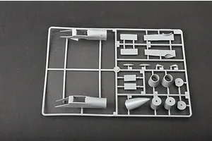 A grey plastic sprue containing various model aircraft parts, including fuselage sections and engine nozzles, on a dark background.