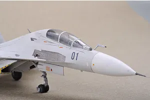 Close-up of a 1/72 scale plastic model of a Russian Su-30 fighter jet, showing the cockpit, nose, and landing gear on a neutral background.